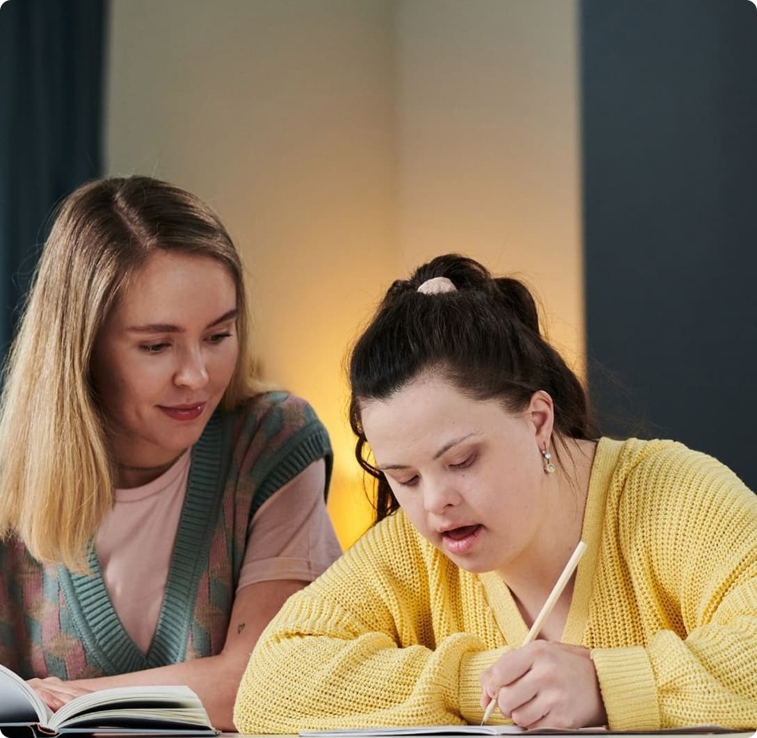 Two people collaborating over notes and a laptop